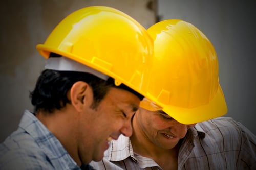 Male construction workers wearing helmets and smiling