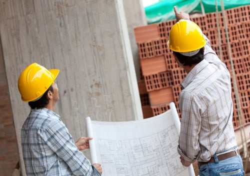 Engineers working and holding a model in a construction