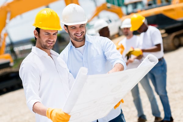 Team of architects at a building site looking at blueprints